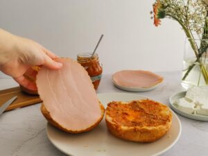 adding a slice of turkey ham on sandwich