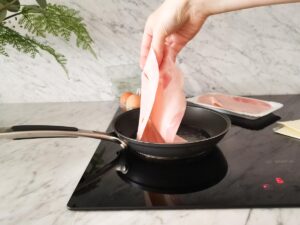 adding ham to pan for fried eggs