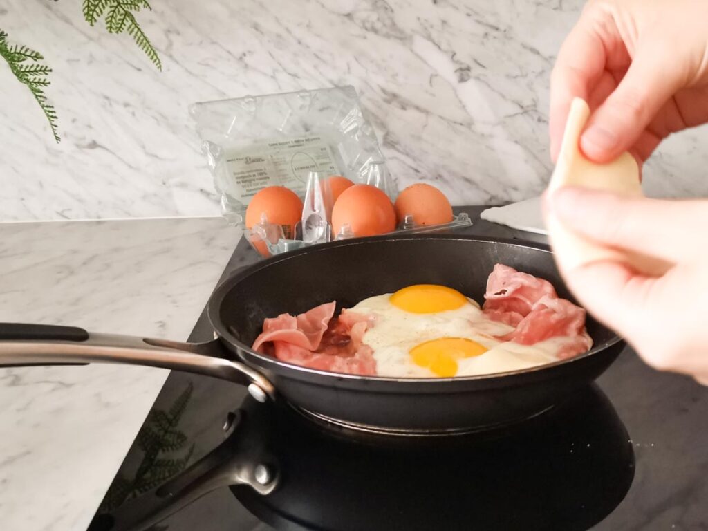 adding sliced cheese to fried eggs