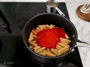 adding tomato sauce to ziti