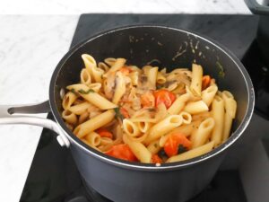 mixing tomato mushroom pasta