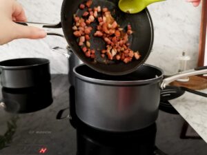 mixing bacon with fusilloni pasta