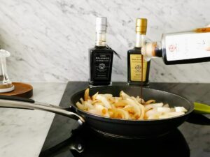 adding balsamic vinegar to onions for caramelizing
