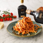 drizzling Balsamic on pesto pasta